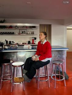 a woman sitting on top of a counter next to two stools