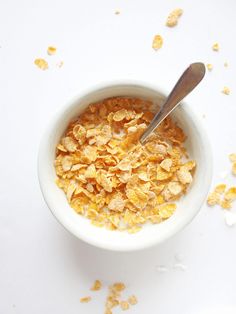 a bowl of cereal with a spoon in it on a white surface next to oats