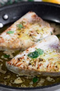 two pieces of fish cooking in a skillet