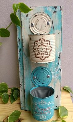 an old tin can is sitting on top of a wooden shelf with some green leaves around it