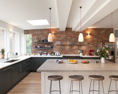 an open kitchen with brick walls and white counter tops, bar stools are in front of the island