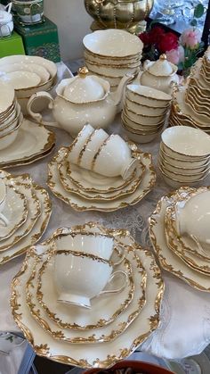 a table topped with lots of white and gold dishes