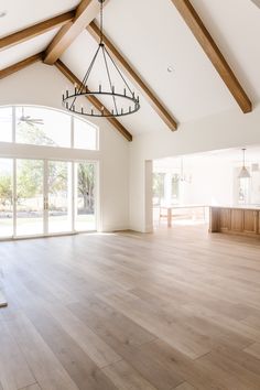 an empty living room with wood floors and large windows