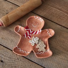 a cookie shaped like a ginger on top of a wooden table next to a rolling pin