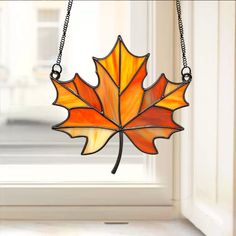 a stained glass maple leaf hanging from a window