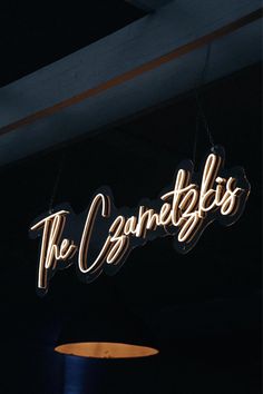 a neon sign that says the contagloss hanging from a ceiling in a dark room