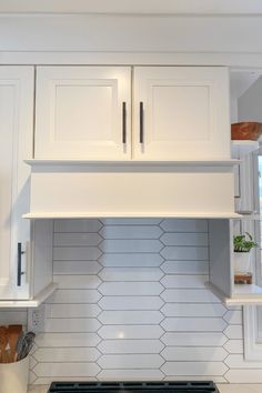 a stove top oven sitting inside of a kitchen next to white cupboards and shelves