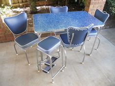 a blue table and chairs sitting on top of a cement floor next to a brick wall