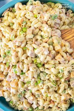 a blue bowl filled with macaroni salad and a wooden spoon in the bowl