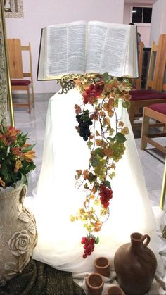 an open book is sitting on a table with flowers and vases next to it