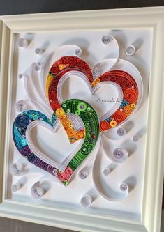 two hearts made out of buttons in a white frame