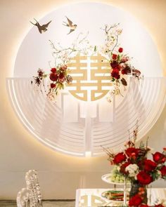 a white table topped with vases filled with red flowers and birds flying over it