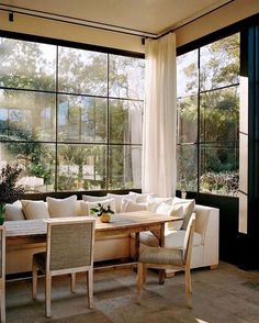 a living room filled with lots of windows next to a white couch and dining table