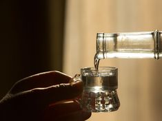 someone is pouring water into a glass cup