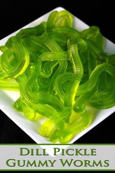 a white plate topped with green worms on top of a black table next to text that reads dill pickle gummy worms