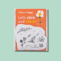 three white stickers with flowers on them in front of a green background and an orange book cover