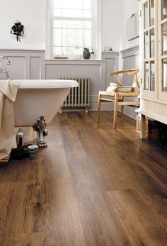 Classic Oak LVP flooring shown in a traditional-styled bathroom with claw foot tub, followed by a close-up angled image. Bathroom Flooring Trends, Flooring Ideas Vinyl, Wooden Bathroom Floor, Design Interior Baie, Best Bathroom Flooring, Oak Timber Flooring, Vinyl Flooring Bathroom