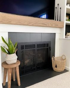 a fireplace with a potted plant on top of it and a basket next to it