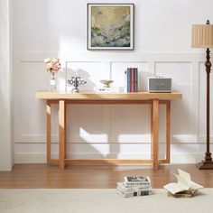 a wooden table with books on it and a lamp in the corner next to it