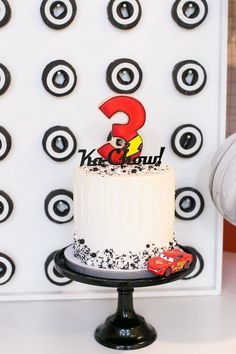 a birthday cake with the number 3 and cars on it is displayed in front of a backdrop