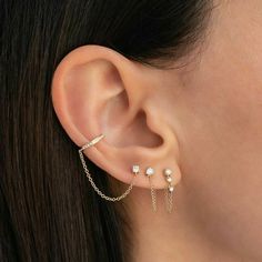 a woman's ear is shown with three different chains attached to the side of her ear