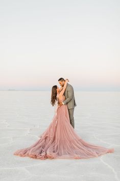 a bride and groom kissing in the middle of an empty salt flat field at sunset