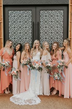 a group of women standing next to each other in front of a door holding bouquets