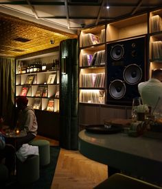 two people sitting at a table in a room with record players on the wall and shelves full of records