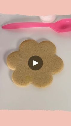 a pink toothbrush next to a cookie shaped like a flower