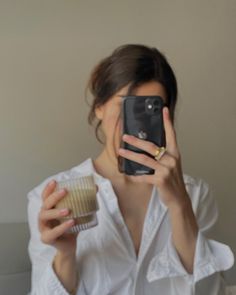 a woman taking a selfie while holding a cupcake