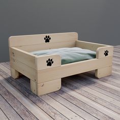 a wooden dog bed with paw prints on the bottom and sides, sitting on a wood floor