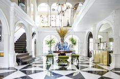 an elegant dining room with black and white checkered flooring, chandelier, and marble staircase