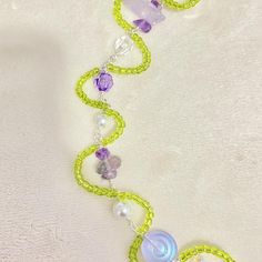 a green and purple beaded necklace on a white surface