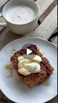 a white plate topped with food next to a cup of coffee on top of a wooden table