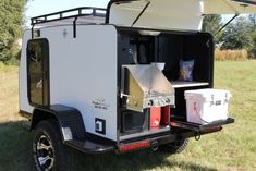 an off - road camper trailer is parked in the grass with its door open