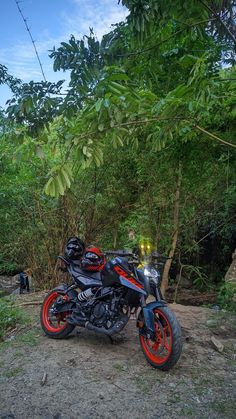 a red and black motorcycle parked next to some trees