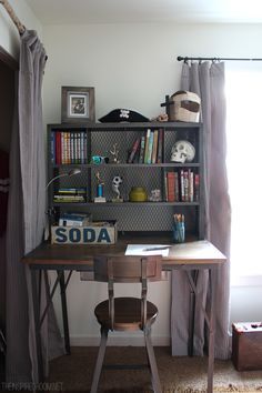 a desk and chair in a room with a book shelf on the wall behind it