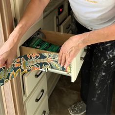 a woman is opening the drawer in her kitchen with an open tie on it's handle