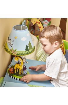 a young boy playing with a toy giraffe on top of a blue table