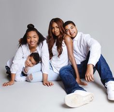 a group of people sitting on the ground posing for a photo with their arms around each other