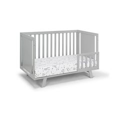 a white crib that is next to a bed with a pillow on top of it