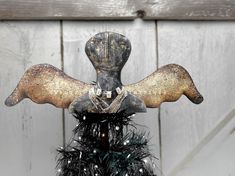 an old metal angel decoration on top of a tree