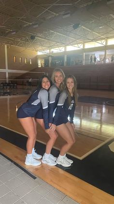 three young women posing for a photo on a basketball court with their arms around each other