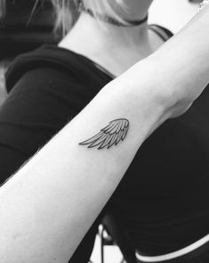 a woman's arm with an angel wing tattoo on the left side of her arm