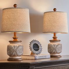 two lamps sitting on top of a table next to a book and a lamp shade