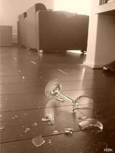 a broken wine glass sitting on top of a wooden floor