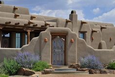 an adobe style house with blue flowers in front