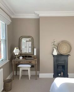 a bedroom with a bed, dresser and mirror in it's corner next to a window