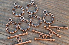 six antique style copper plated metal beaded charms on a wooden surface with spacers