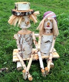 two wooden dolls made to look like they are sitting in the grass